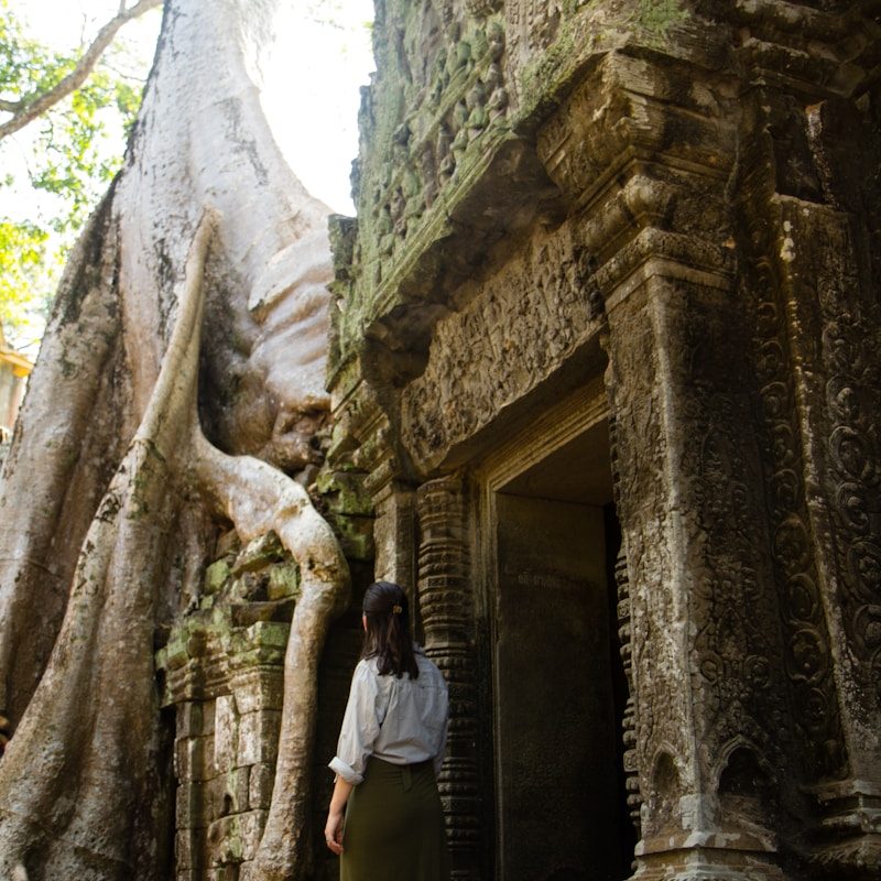 woman standing near concrete door and tree during daytime